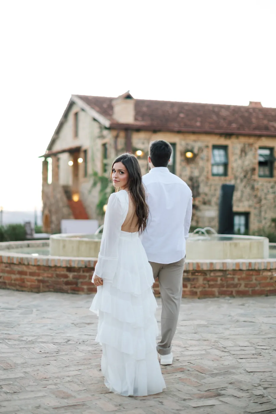Casal caminhando para a fonte, ela olhando para trás