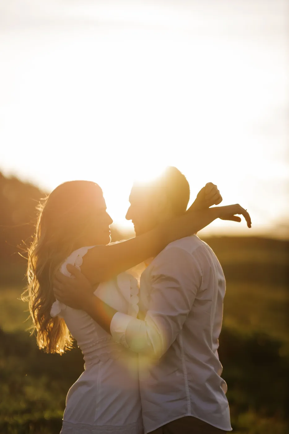 Casal abraçado no contraluz do pôr do sol