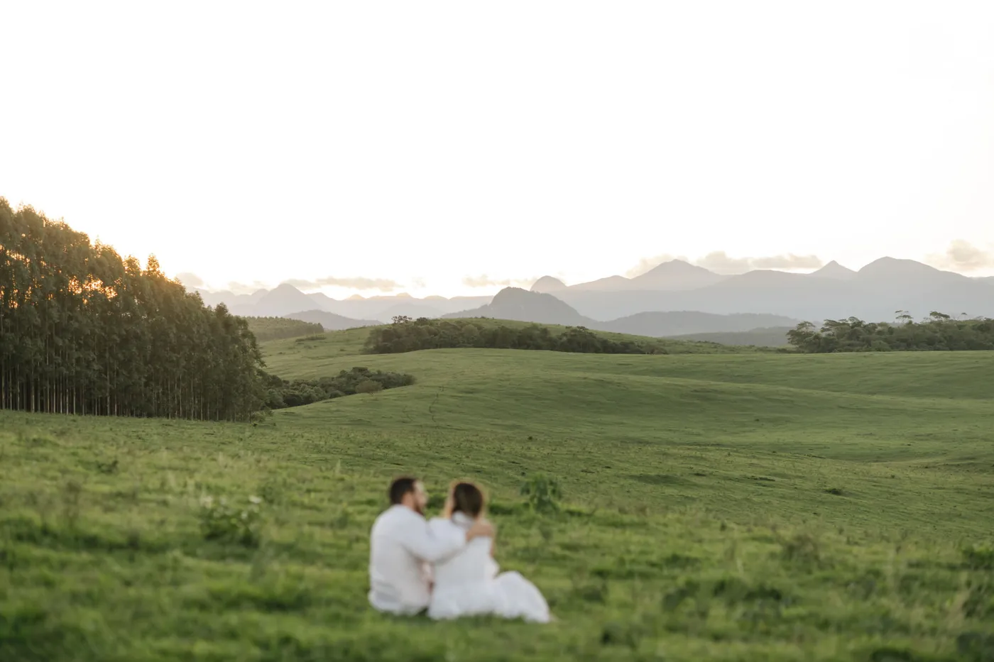 Casal sentado no campo, olhando as montanhas