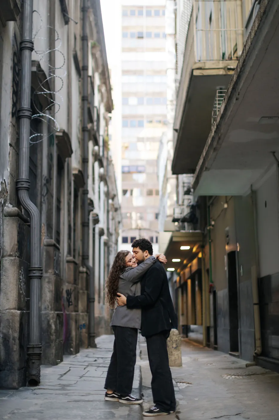 Casal se beijando num beco entre prédios antigos